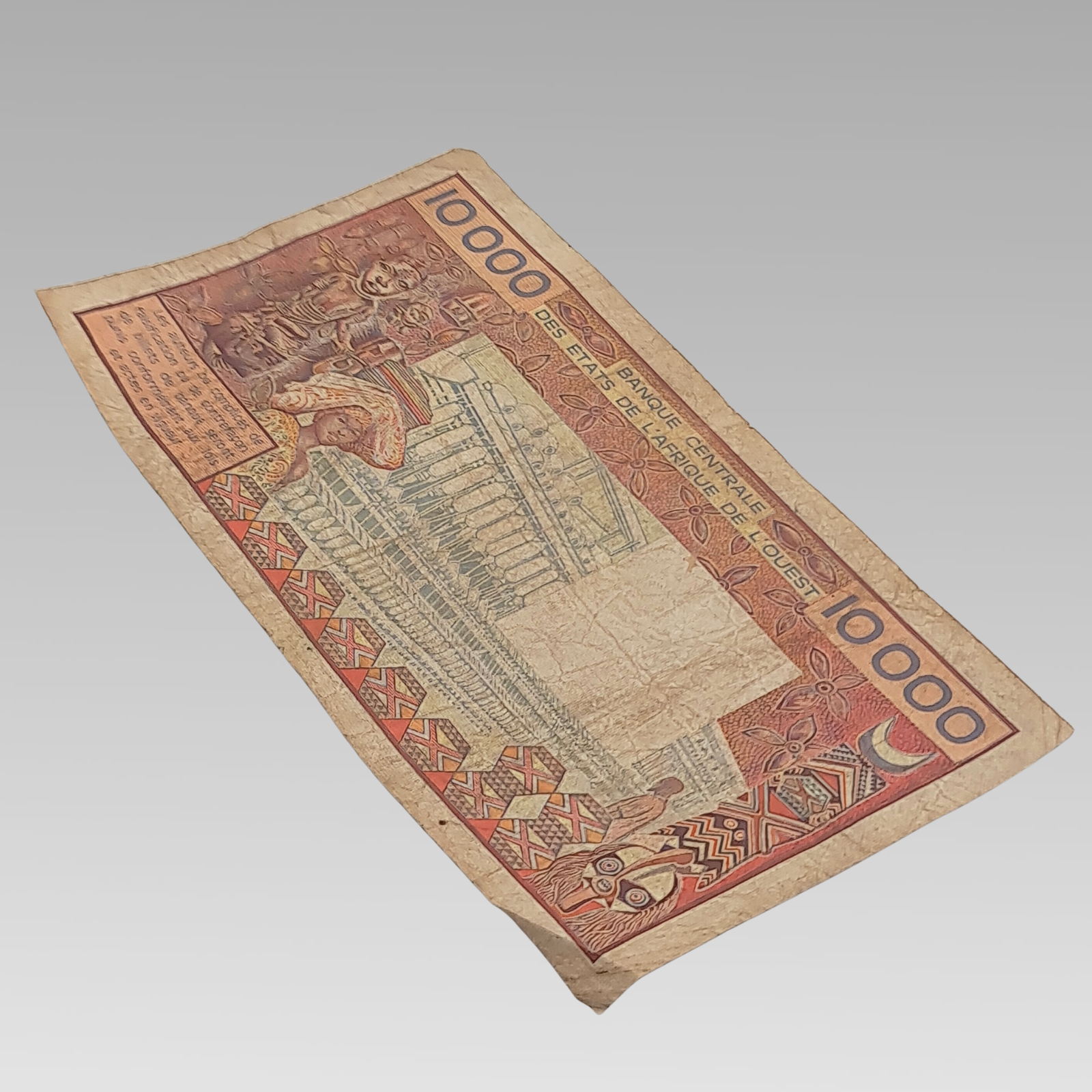 Reverse of BCEAO 10000 Francs banknote featuring African artwork and architecture